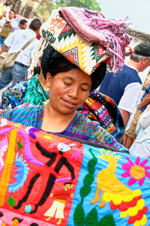 Mayan Indian woman wearing a traditional huipil sells weavings in the city of Antigua in the highlands of Guatemala - 22nd of April 2011のeditorial素材