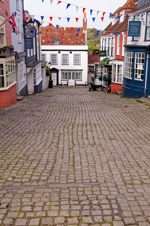 Lymington Hampshire - colorful rendered walls and bay windows on shopfronts along hilly cobbled Quay Hill street in England UK - 20th of May 2021のeditorial素材