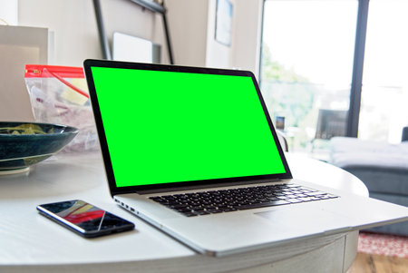 Young professional man using a laptop with a green screen - wearing a fashion watch. Work from home - London, United Kingdom, 1st of June 2019のeditorial素材