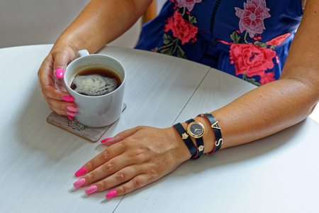 Woman having a cup of coffee wearing fashion jewelery - London, United Kingdom, 1st of June 2019