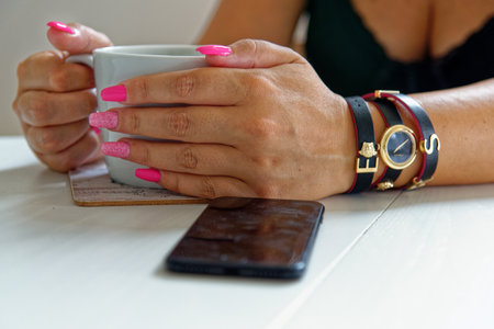 Young woman having a cup of coffee wearing fashion jewelery - London, United Kingdom, 1st of June 2019のeditorial素材