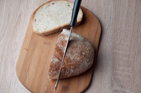 Cutting board, bread and a knife lying on a wooden table