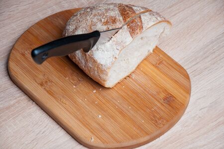 Cutting board, bread and a knife lying on a wooden table