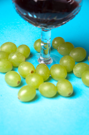 glass of wine and grapes, isolated on blueの写真素材
