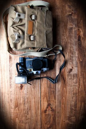 Old camera and bag, wooden background
