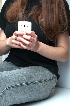 Girl holding a white smartphone. White backgroundの写真素材