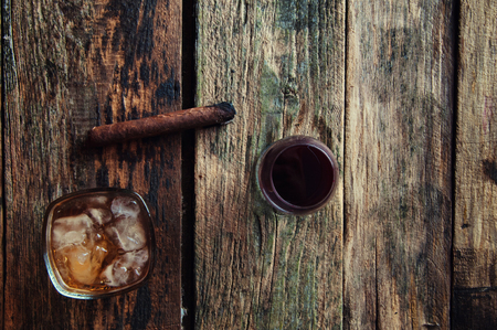 Lit cigar, wine and whiskey on a wooden background from above.の写真素材