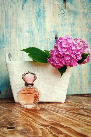 Perfumes and hydrangea in a white basket on blue wooden backgroundの写真素材