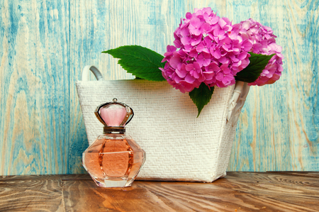 Perfumes and hydrangea in a white basket on blue wooden backgroundの写真素材
