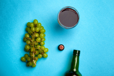 Glass of wine and green grapes, isolated on blueの写真素材
