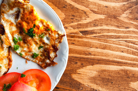 fried eggs with tomato on a wooden table
