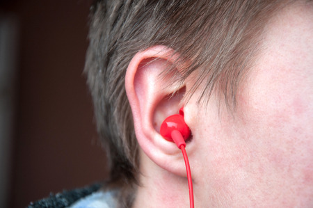 Close up of red headphone in mans ear.の写真素材