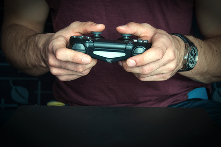 Man holding game controller sitting on ble sofa.