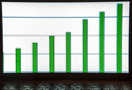 Laptop with business graph placed on wooden desktop.の写真素材