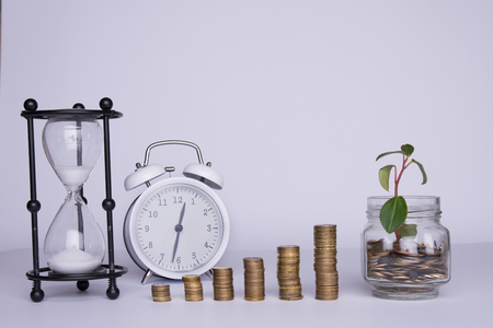 stacks of money and hourglass on a white background.の写真素材