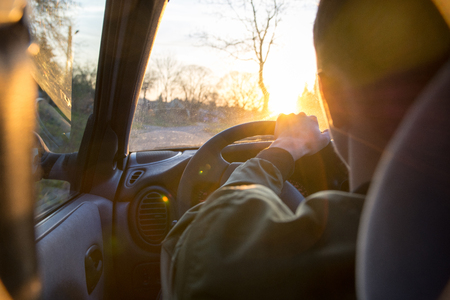 young man driving a car through the town during sunsetの写真素材