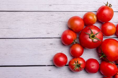 tomatoes as background on the right on a white wooden background.