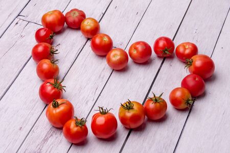 heart-shaped tomatoes on white wooden backgroundの写真素材
