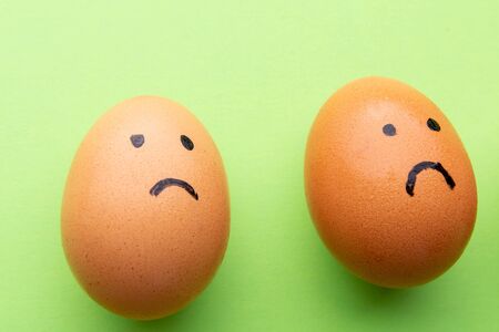 Two sad eggs on a green background.