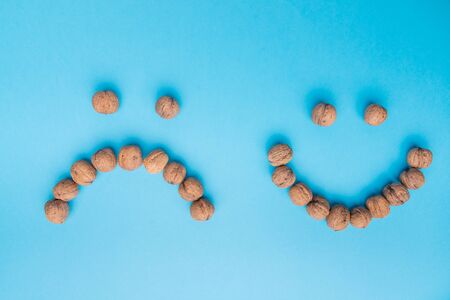 A sad and happy face arranged with walnuts. From above. Text space.の写真素材