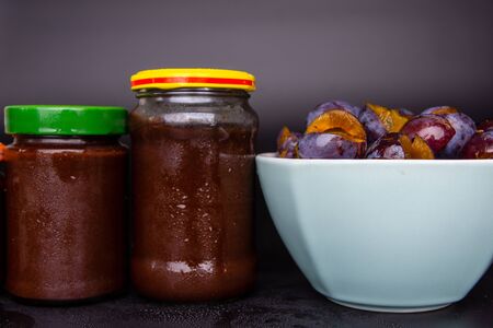 Jars and a bowl full of plum jam.の写真素材