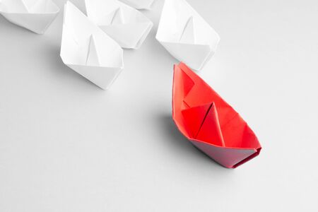 Leadership concept using red paper ship among white