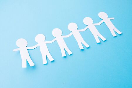 White paper people holding hands. Blue background.の写真素材
