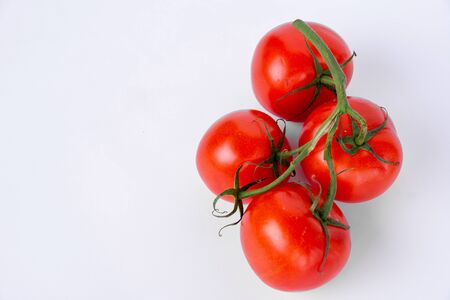 Tomatoes and a green stalk on a white backgroundの写真素材