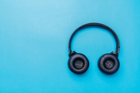Black headphones in the center of the photo from the top on a blue background