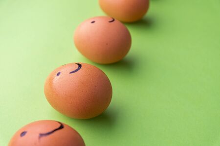 Smiling and sad eggs on a green background.の写真素材