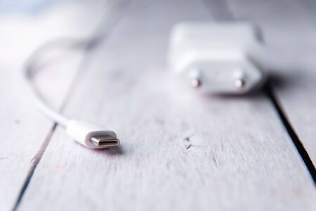 White phone charger on a wooden white background.の写真素材