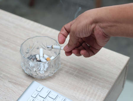 hand holding cigarette with ashtray isolated on whiteの写真素材