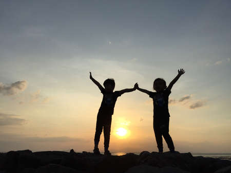 silhouette of  two sibling playing on sunset backgroundのeditorial素材