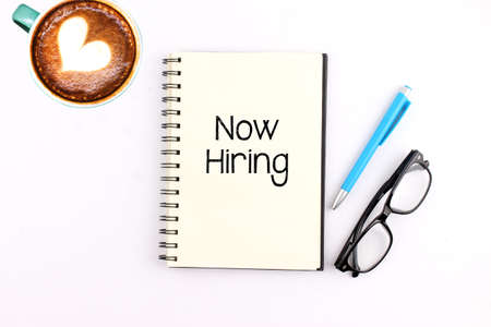 Now Hiring writing on notebook with pen and coffeeの写真素材