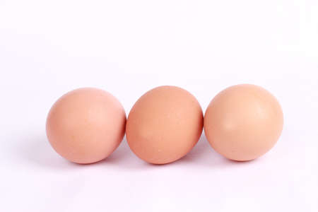 Close-up view of raw chicken eggs in egg box on white wooden background
