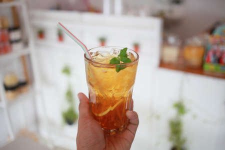 Hand hold a ice lemon tea on cafe backgroundの写真素材