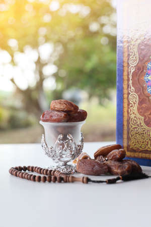 Ramadan kareem with dates, rosary and holy quran on fresh green background