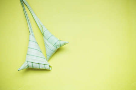 Top view ketupat or rice dumpling icon of the hari raya.yellow background and copy spaceの写真素材