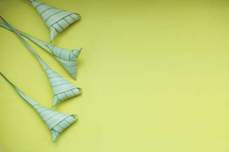 Top view ketupat or rice dumpling icon of the hari raya.yellow background and copy spaceの写真素材