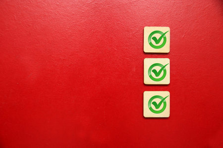Check mark on wooden blocks on red background. Checkmark concept.の写真素材