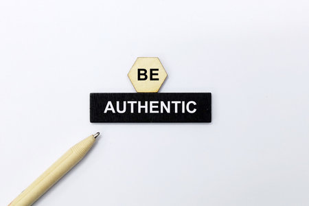 Be Authentic written on black wooden block with pencil on white backgroundの写真素材