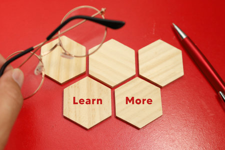 Learn more concept with wooden blocks and eyeglasses on red backgroundの写真素材