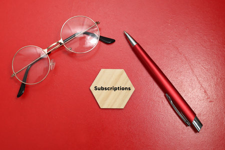 Pen and glasses on a red background with the word subscriptions