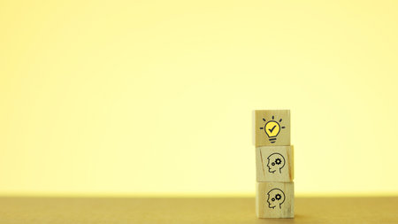 Wooden blocks with light bulb and idea icon on yellow background.