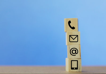 Wooden blocks with phone and email icon on blue background. Business conceptの写真素材