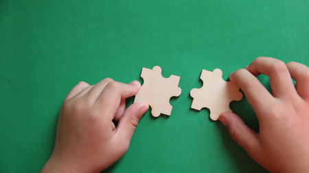 Hands connecting two jigsaw puzzle pieces. Teamwork concept.