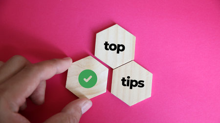 Top tips concept with wooden blocks and green tick on pink background.の写真素材