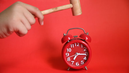 Alarm clock and hammer on red background, closeup. Time management concept