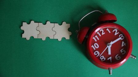 Alarm clock and jigsaw puzzle on green background. Time management concept