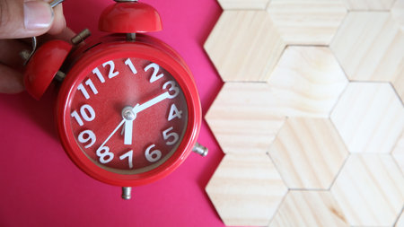 Red alarm clock on pink background with wooden cubes. Time concept.の写真素材